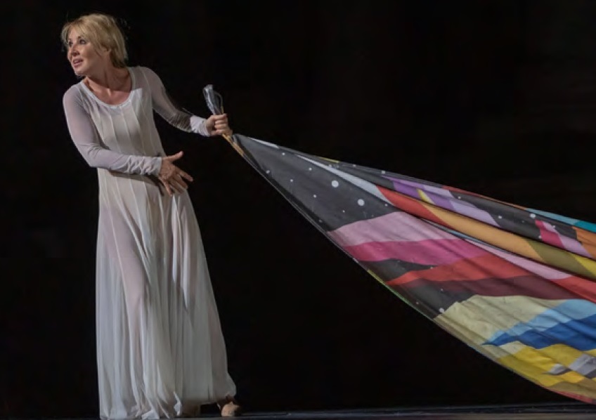La actriz Cayetana Guillen cuervo vestida de blanco arrastra una bandera multicolor