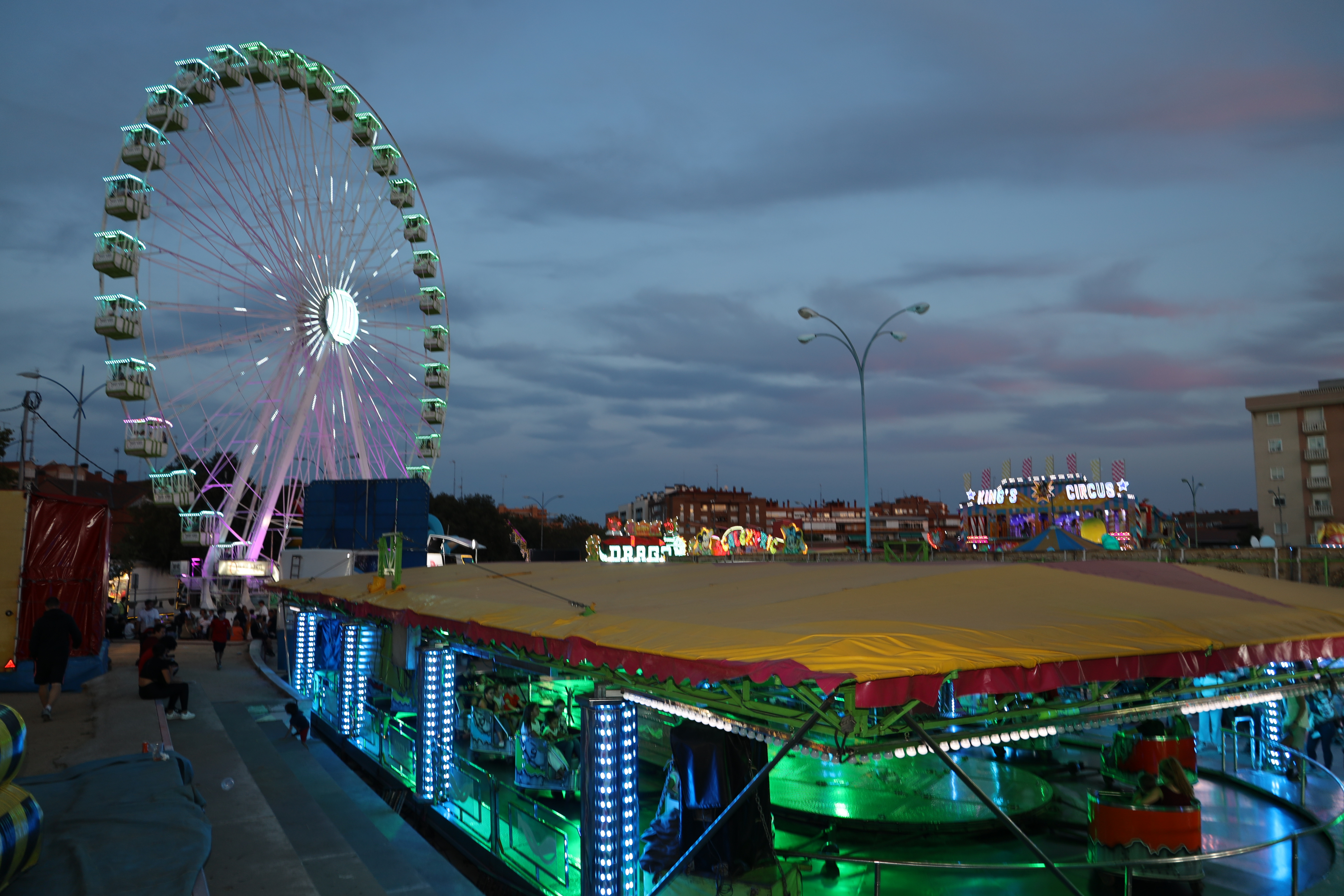 Foto nocturna del recinto ferial con la noria y atracciones iluminadas
