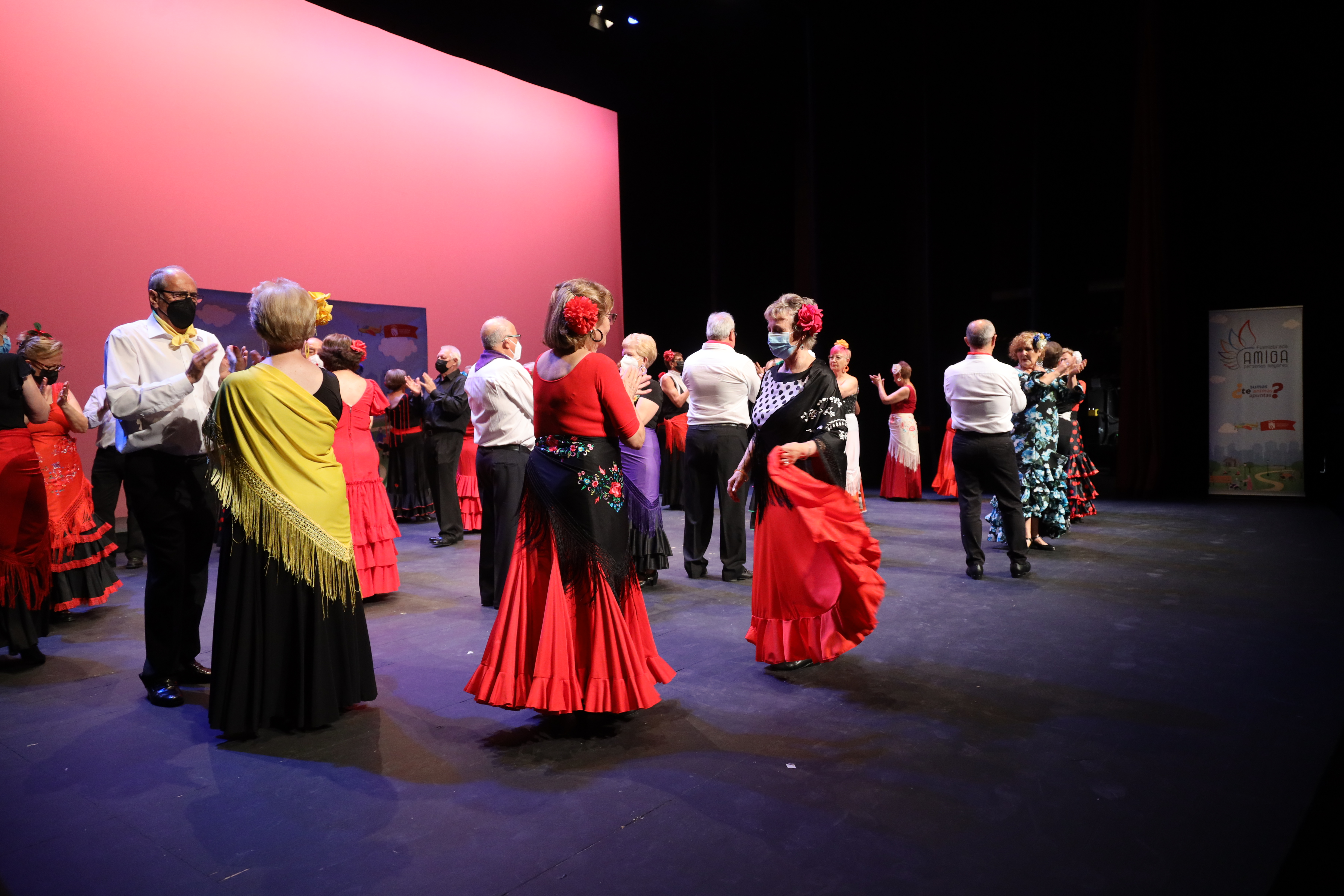 Personas mayores bailando sevillanas en el escenario de un teatro