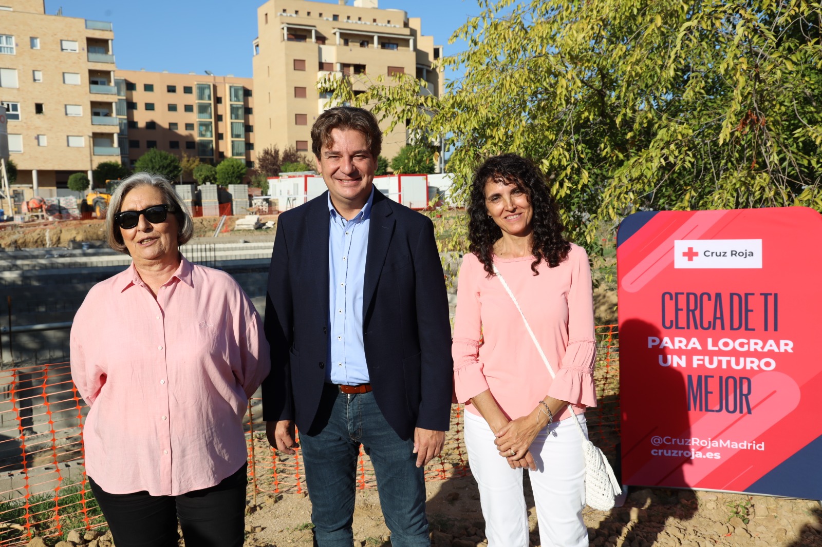 El Alcalde y las presidentas regional y local de Cruz Roja en la calle con el inicio de unas obras y un cartel rojo con una Cruz Roja 