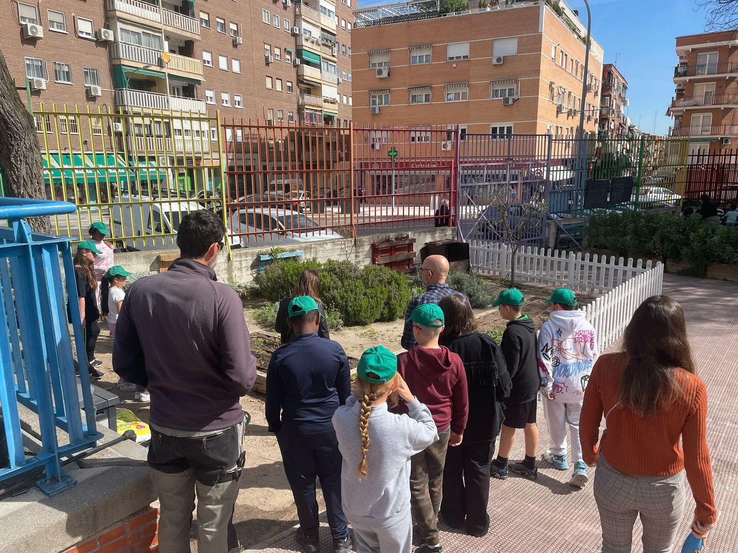 Un grupo de niños y niñas con sus profesores observan una de las instalaciones para hacer compost en el huerto del colegio