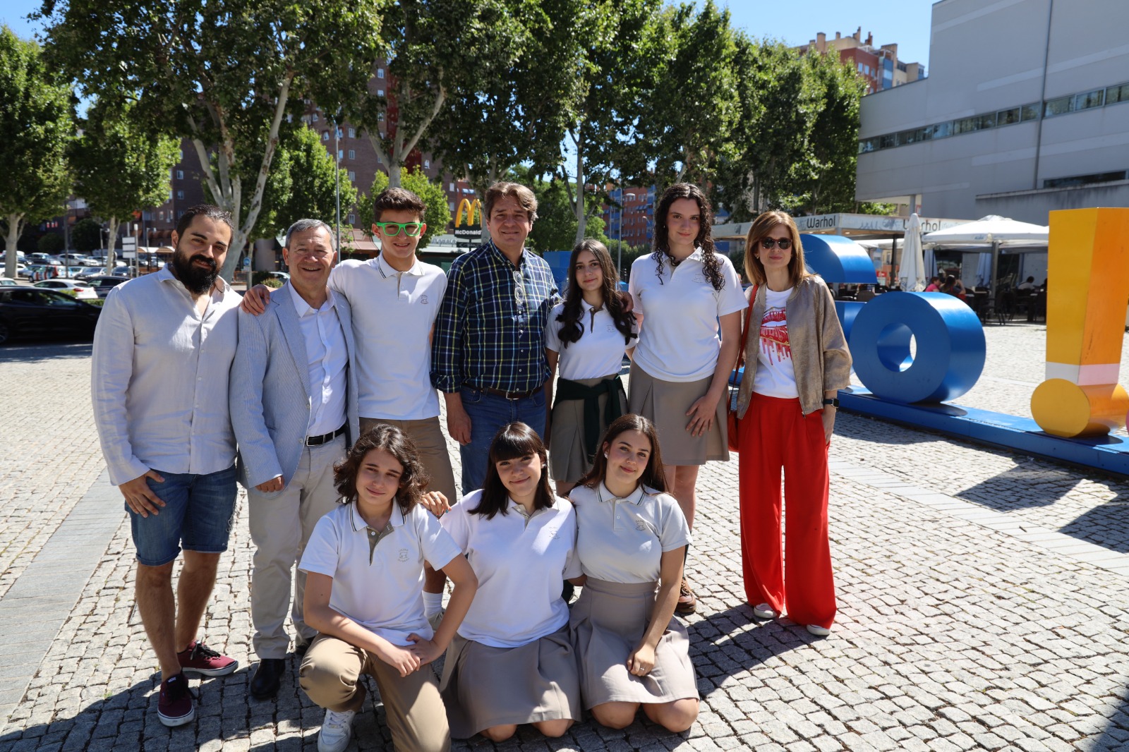 Seis estudiantes junto al alcalde, el concejal, un profesor y la directora del instituto en una plaza