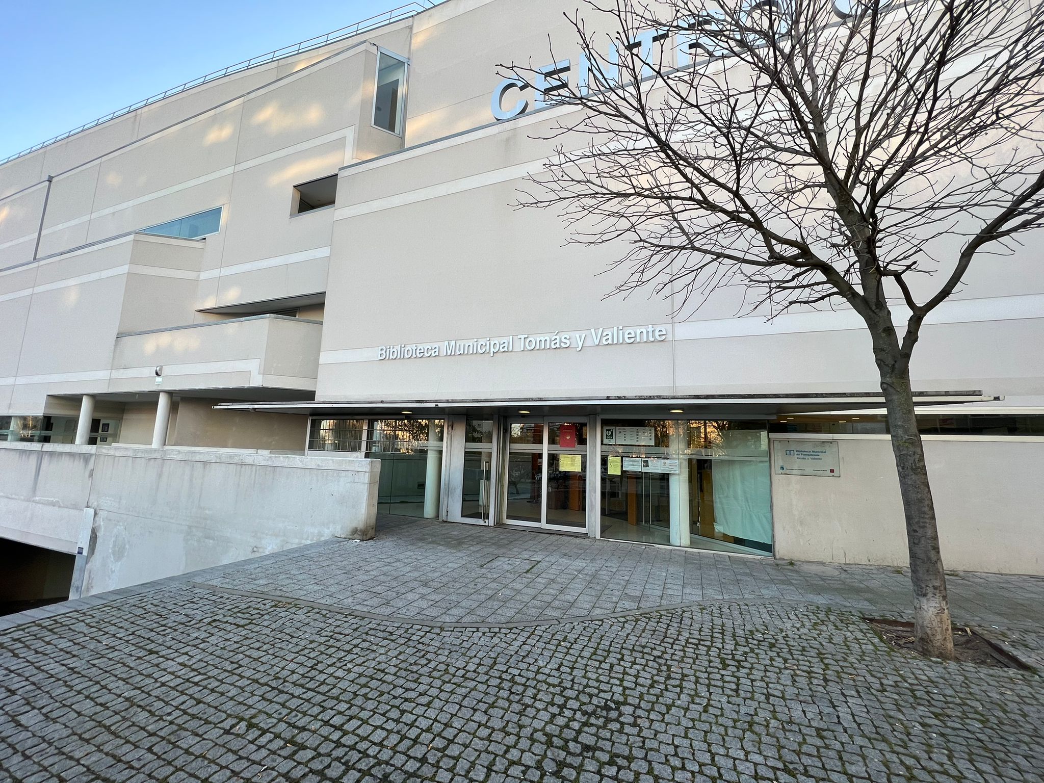 Fachada de un edificio gris y en la entrada suelo empedrado