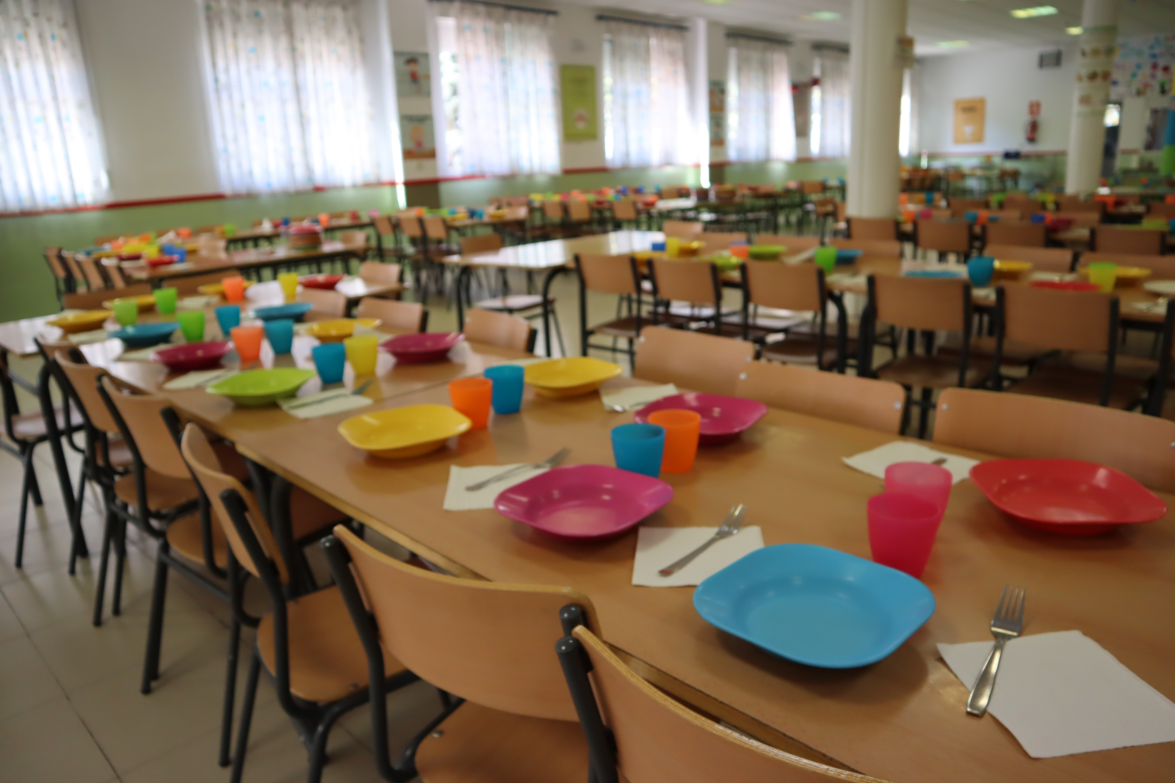 Comedor escolar vacío de alumnos con mesas, sillas y vajilla  