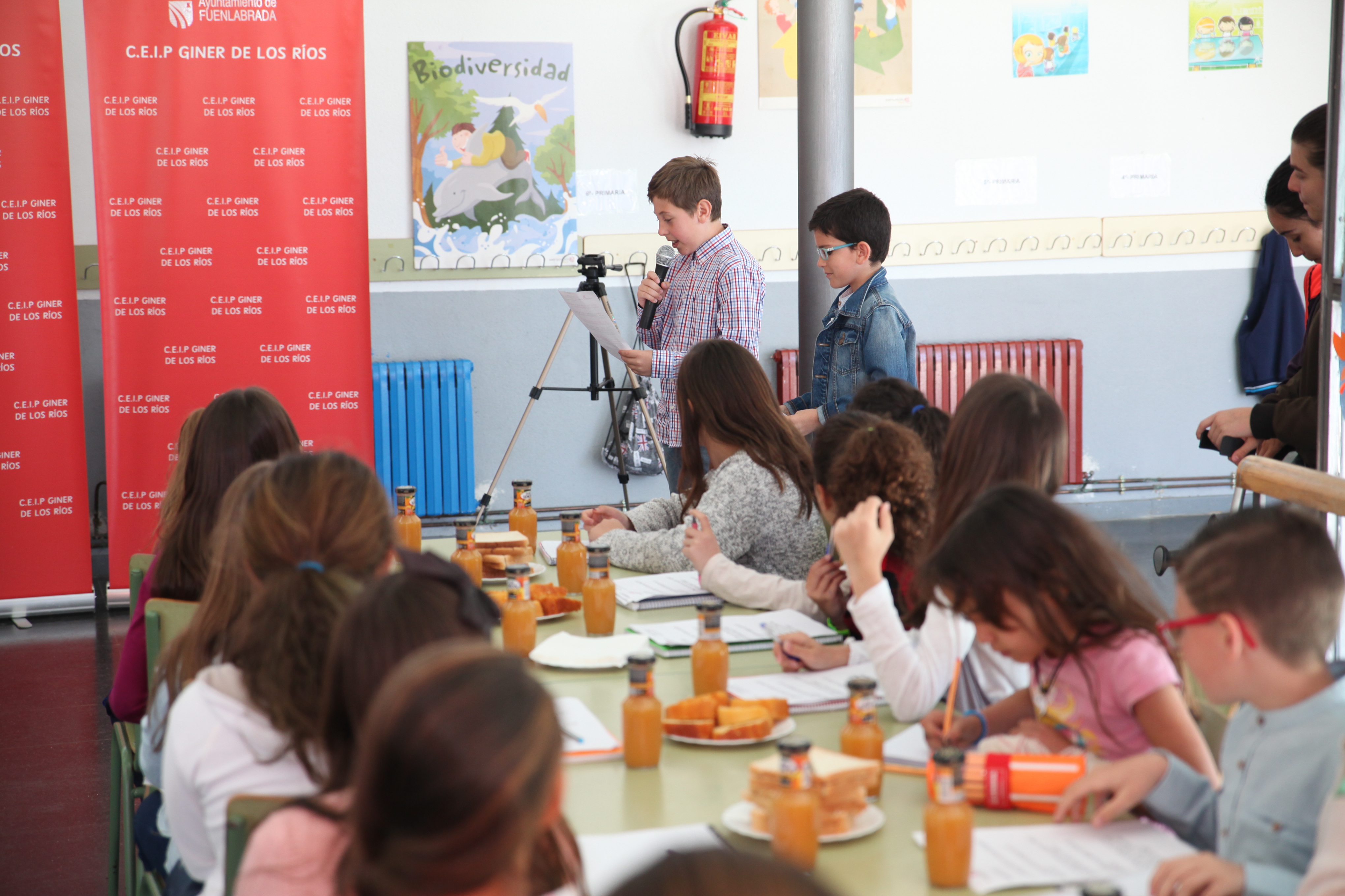 Una docena de niños y niñas desayunan en el comedor de un colegio
