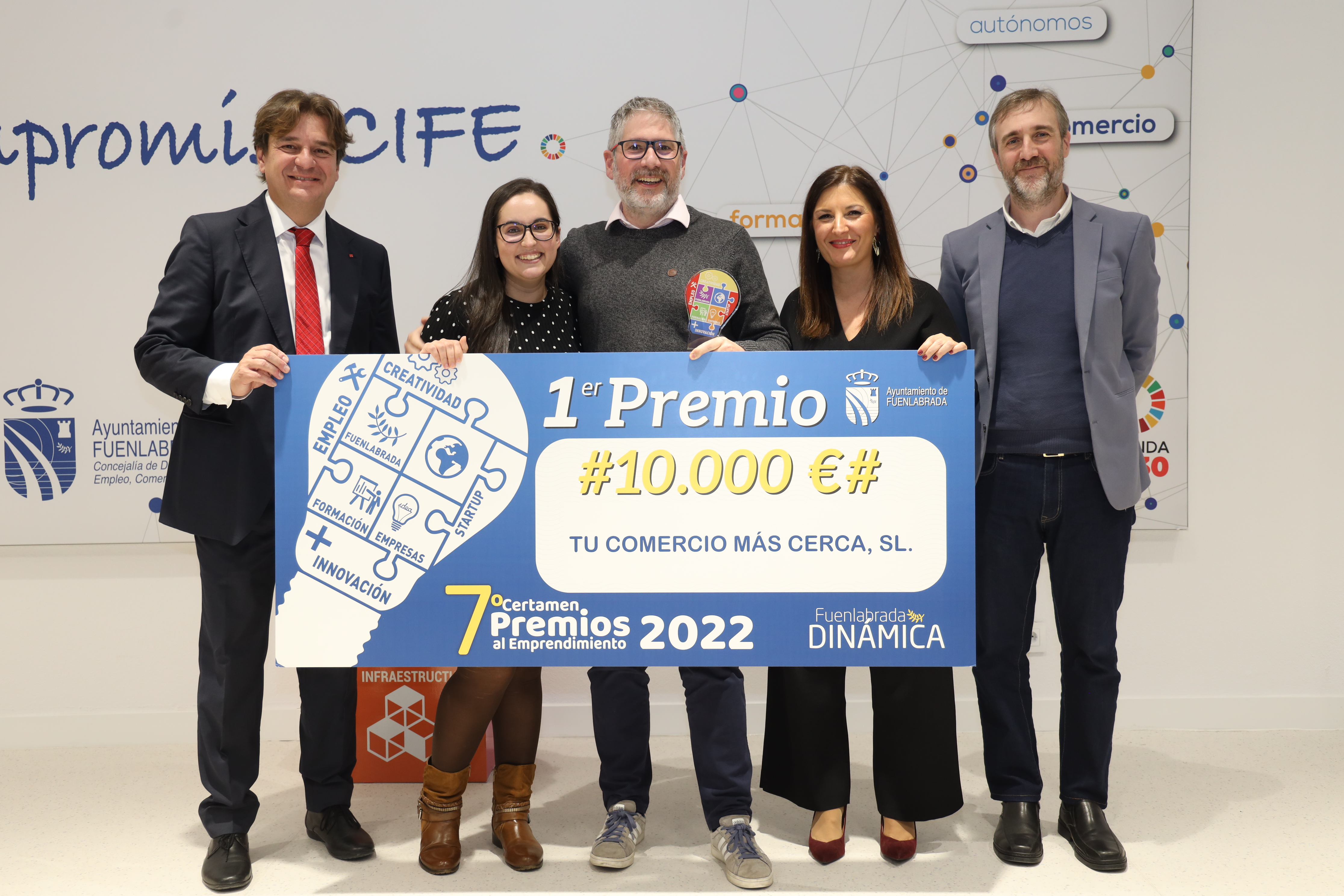 Grupo de personas posando con un gran cheque de cartón piedra  