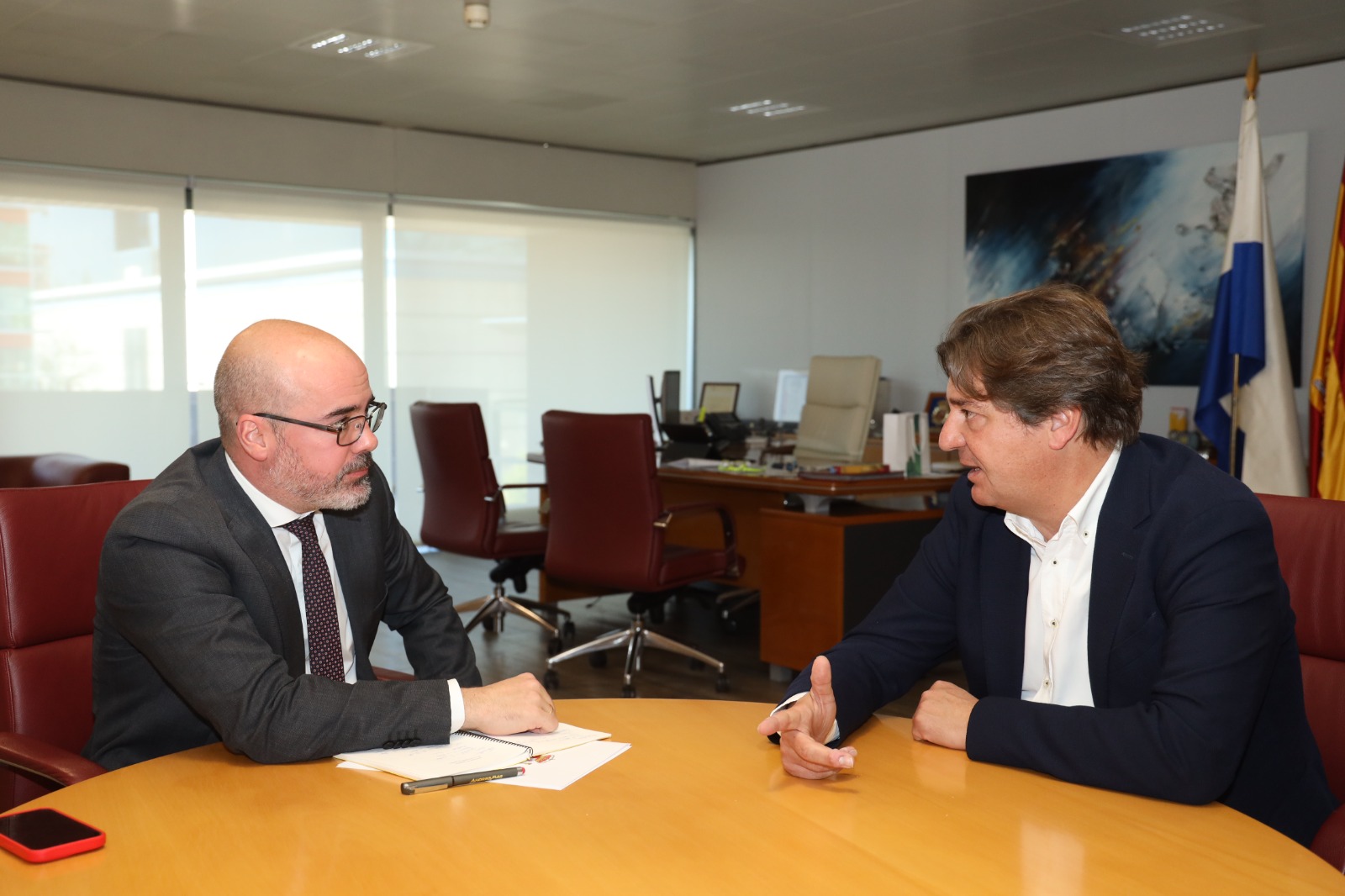 Dos hombres conversan sentados a una mesa