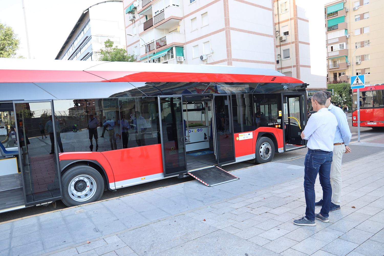 Dos hombres contemplan un autobús con la rampa de acceso activada