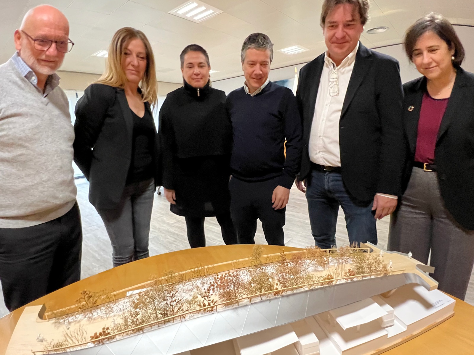 Media docena de hombres y mujeres mirando una maqueta