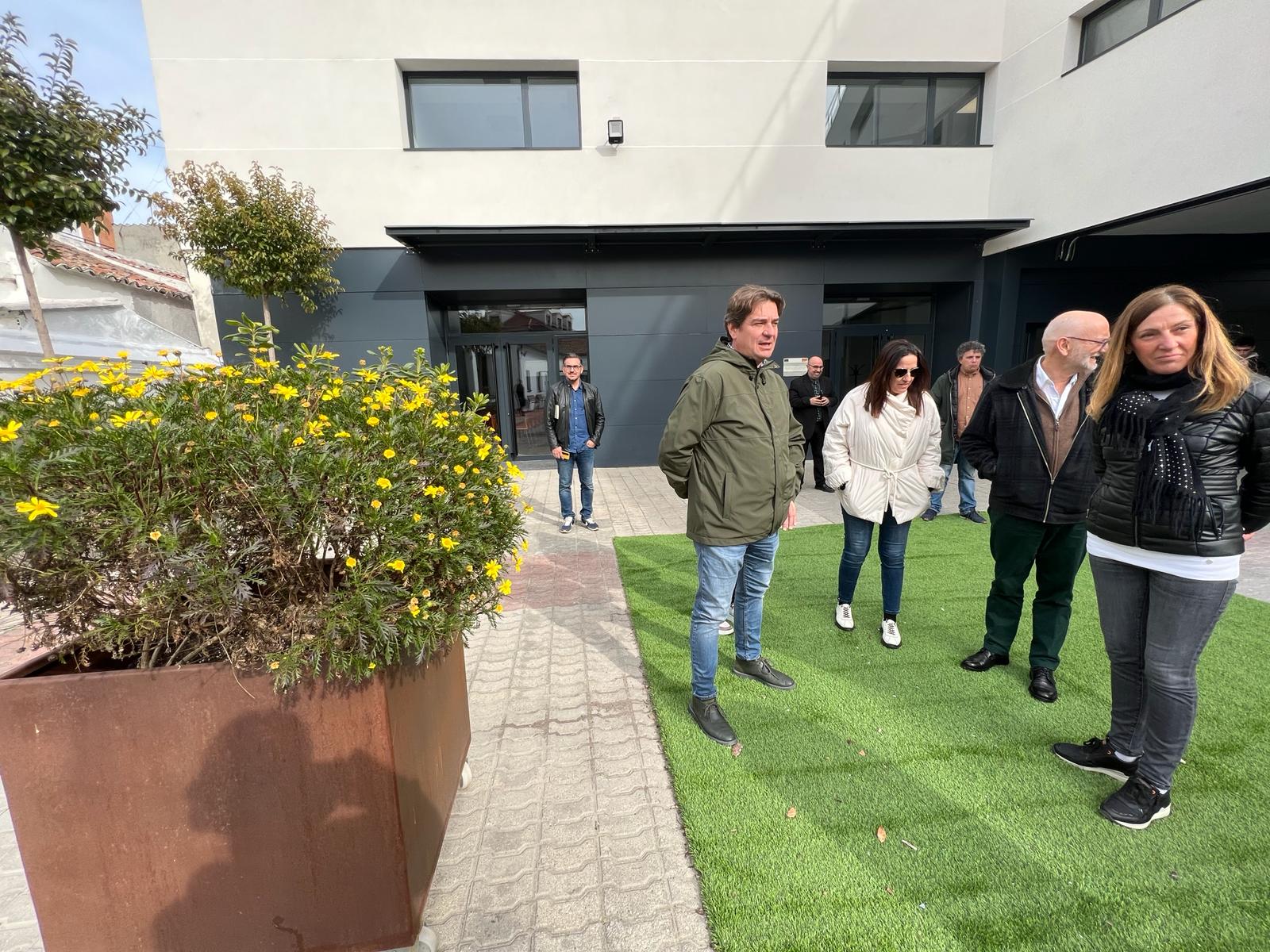 Una docena de personas en un patio con una gran maceta con plantas