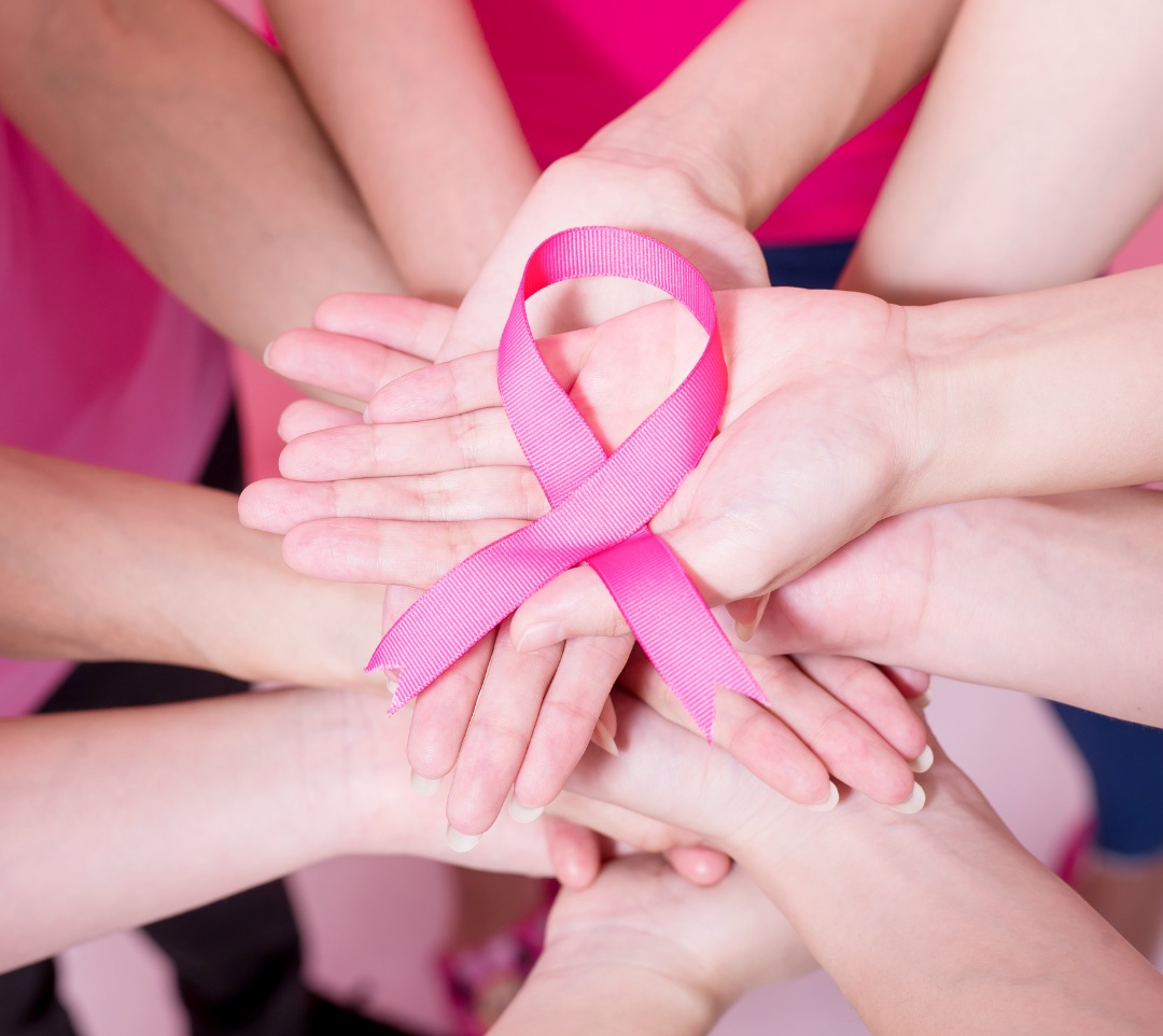 Manos sujetando un lazo rosa