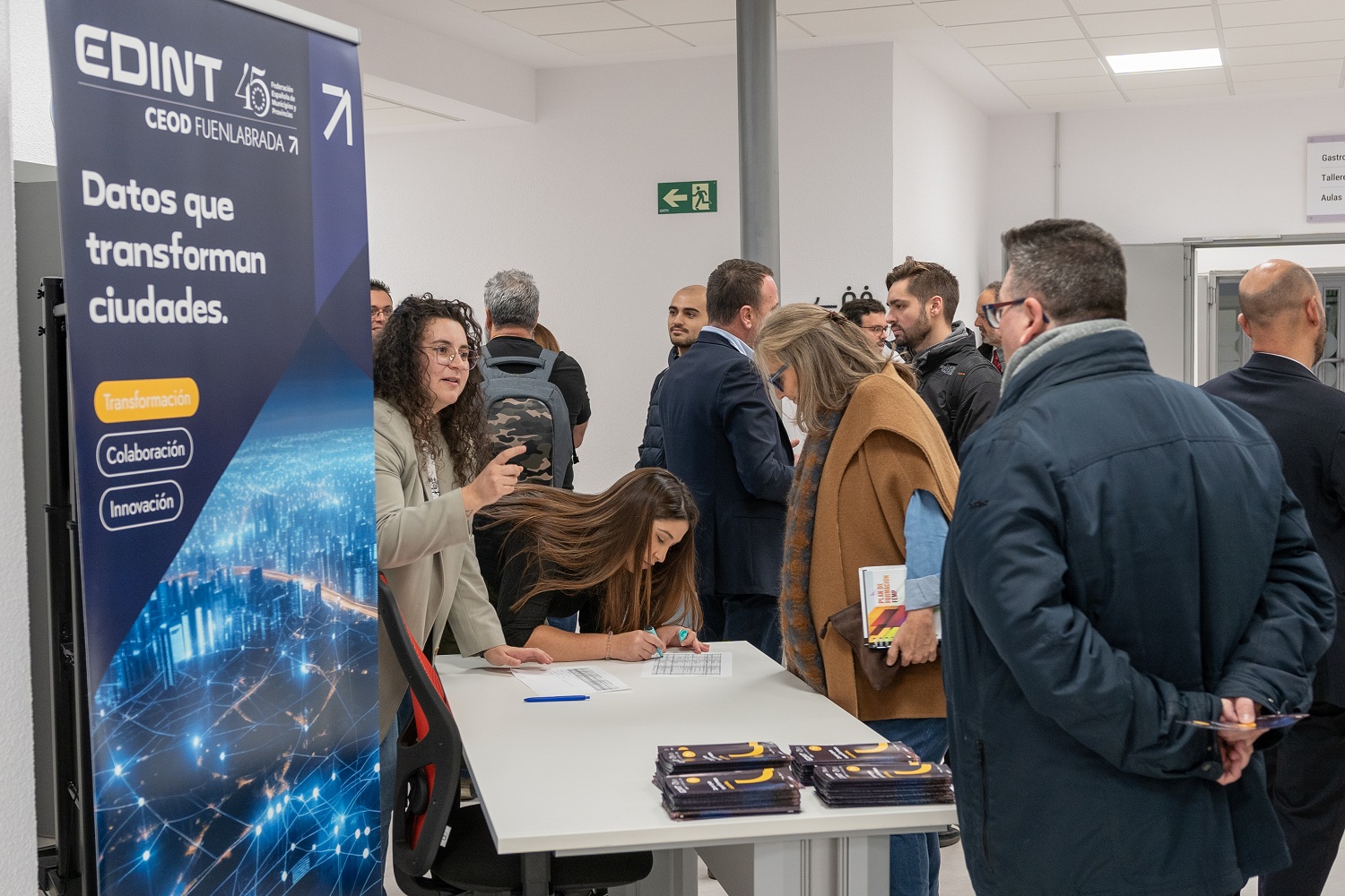 Personas en un hall con un cartel de EDINT: 