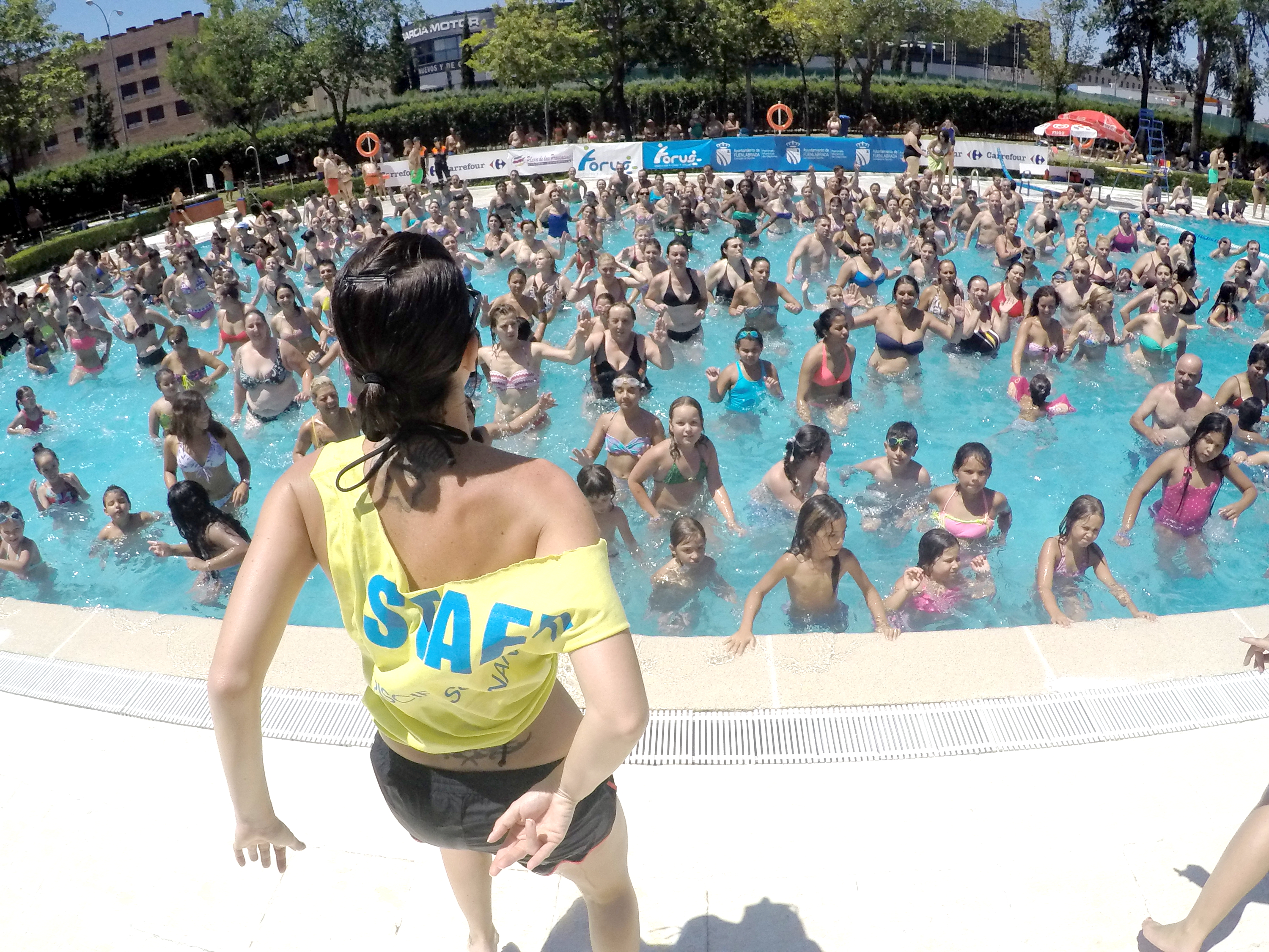 Personas de todas las edades dentro de la piscina siguen la coreografía de una monitora  