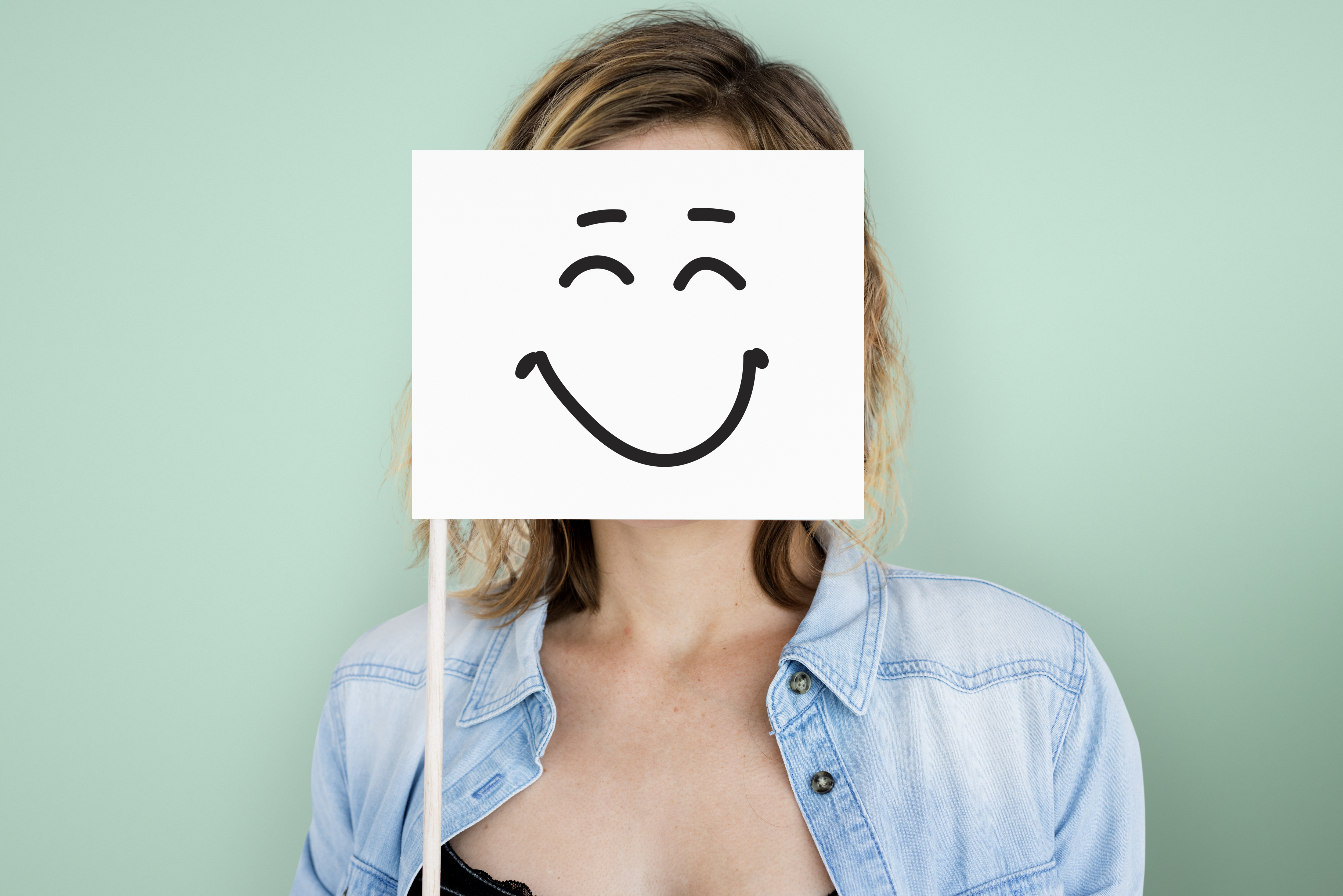 Mujer con un dibujo sonriente delante de su cara