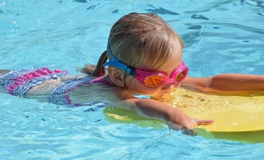 Niña con una tabla en la piscina. Imagen de Jan Haerer en Pixabay