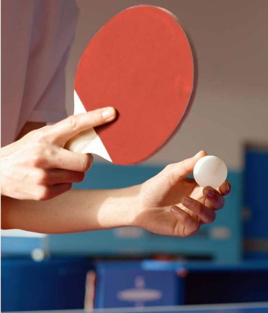 Manos sosteniendo una pelota y una pala de tenis de mesa